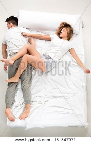 The young lovely couple lying in a white bed, love lconcept, top view