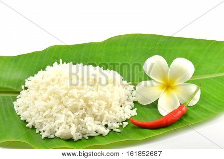 Rice, red chilies and white flower on the leaf of banana tree isolate