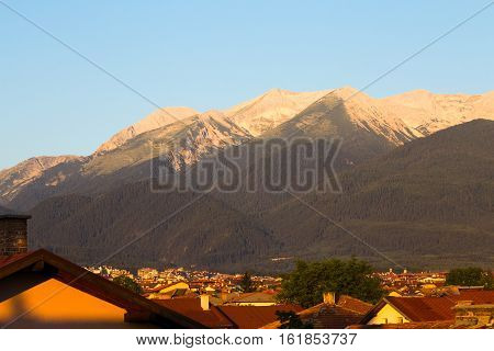 Morning sunrise view in glowing light of the Pirin Mountain and rooftops of the town of Bansko in summer a popular Bulgarian ski resort and tourist destination