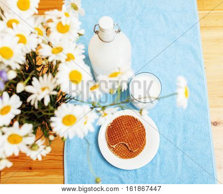 Simply stylish wooden kitchen with bottle of milk and glass on table, summer flowers camomile, healthy foog moring concept noone close up