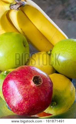 apples, pomegranate and lemons in a bowl