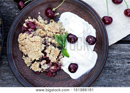 Homemade Cherry crumble wiht ice cream and cherries on an old wooden table background.Selective focus.