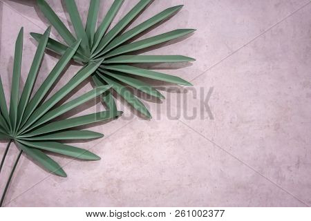 Decorative Artificial Green Palm Leaves On Concrete Wall For Nature Background With Copy Space.