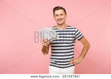 Portrait Of Smiling Excited Young Man In Striped T-shirt Holding Bundle Lots Of Dollars, Cash Money,