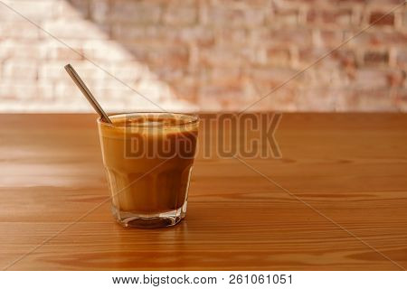 Flat White Coffee In Transparent Glass On Table In Cafe. It Is Espresso-based Coffee Drink Consistin