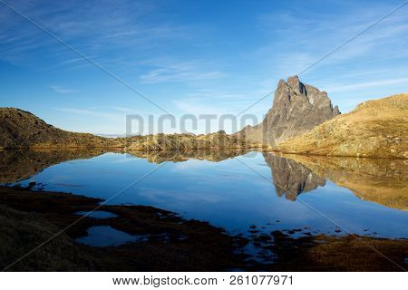 Midi Dossau Peak reflected in a lake. Ossau Valley, Pyrenees National Park, Pyrenees, France.