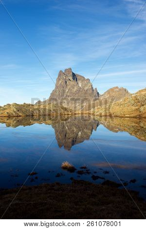 Midi Dossau Peak reflected in a lake. Ossau Valley, Pyrenees National Park, Pyrenees, France.
