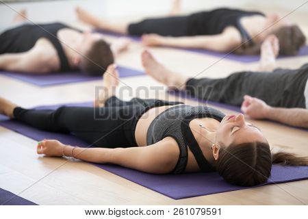 Group Of Young Sporty People Practicing Yoga, Doing Dead Body