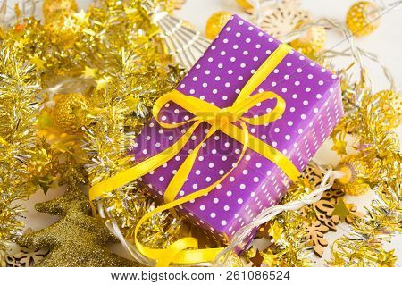 Violet Elegant Present With Yellow Ribbon On Golden Tinsesl And Garland