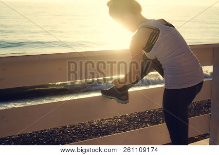 Slim Woman Ties Up The Shoelaces. Healthy Lifestyle Concept. Workout Outdoors By The Sea.