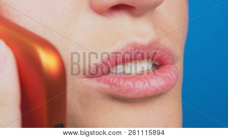 Close-up, Female Lips Without Makeup Talking On A Red Mobile Phone, Against A Blue Background.