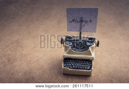 Retro Syled Tiny Typewriter Model On A Brown Background