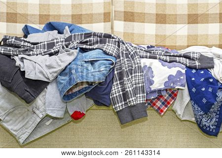 Lot Of Wrinkled Clothes Lying On Sofa