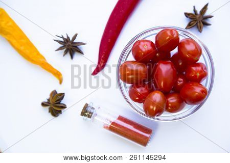 Dry Spices And Herbs In Glass Jar With A Cork, A Bowl Of Cherry Tomatoes And Chili Peppers, White Ba