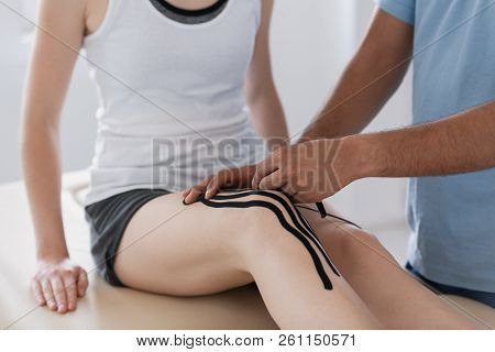 Close-up On Physiotherapist Putting Tapes On Patient's Leg During Kinesiotaping