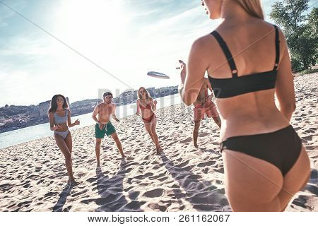 Time With Friends. Group Of Young People Playing Freesby On The Beach
