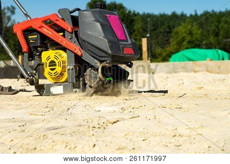 Builder With Vibratory Plates Seals The Base Sand For Pouring Concrete.