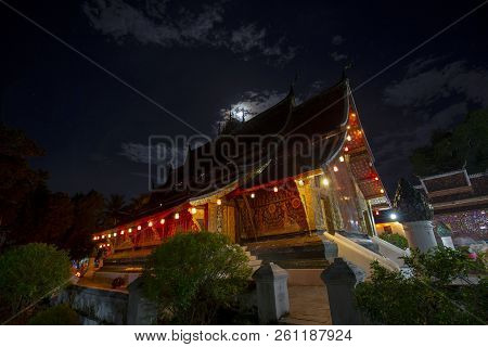 Wat Xiengthong With The Light Of A Nearly Full Moon Behind In Luang Prabang, Laos.
