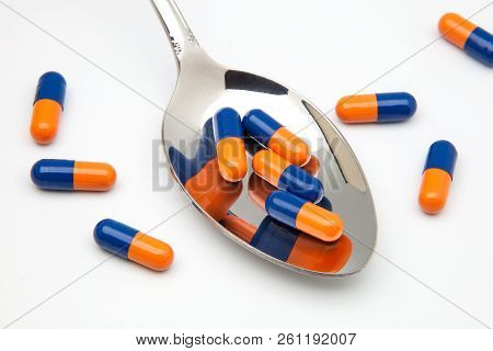 Spoon With Capsulas Medicas On White Background