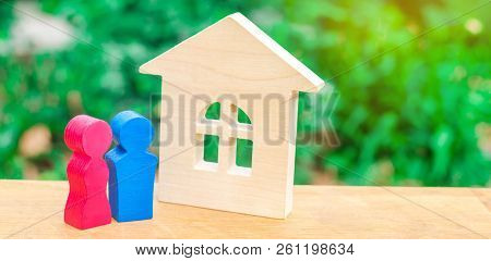 Wooden House And A Young Pair Of Lovers. Affordable Housing For Newlyweds. Stability And Confidence 
