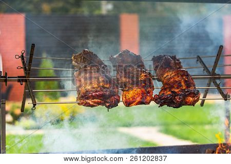 Shish Kebab Roasts On The Grill. Three Pieces Of Pork Are Under The Fire In The Smoke In The Street 