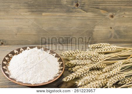 Harvest Of Wheat Spikelets And Flour On Wooden Background