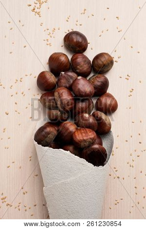 high angle view of some chestnuts in a paper cone, on a wooden table