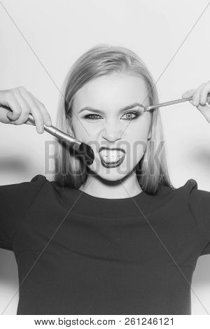 Woman Winking And Angry With Makeup Brushes. Funny Woman With Long Blond Hair In Blue Dress On White