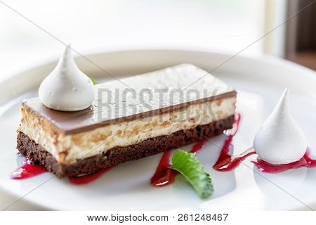 Tasty Cheesecake On White Plate With Jam And Green Leaf.