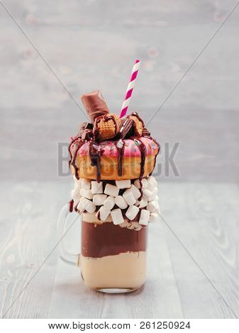 Chocolate And Donuts Extreme Milkshake With Marshmallow And Other Sweets In Mason Jar On Gray Wooden