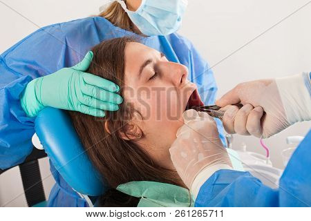 Surgeon Removing The Wisdom Tooth With His Assistant