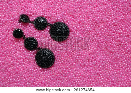 Black Ring And Earrings With Precious Stones On The Background Pink Beads