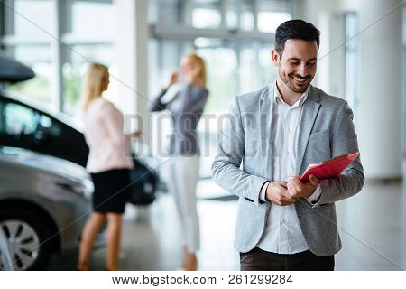 Handsome Salesman At Car Dealership Selling Vehichles