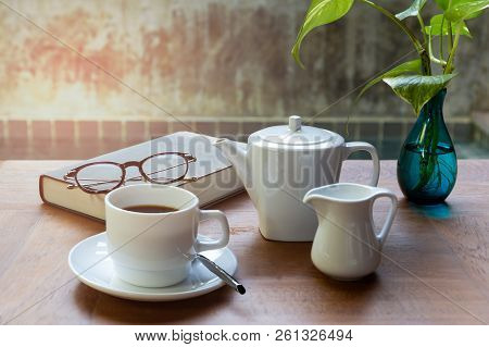 Cup Of Coffee And Glasses On Top Of Readbook On Wood Table