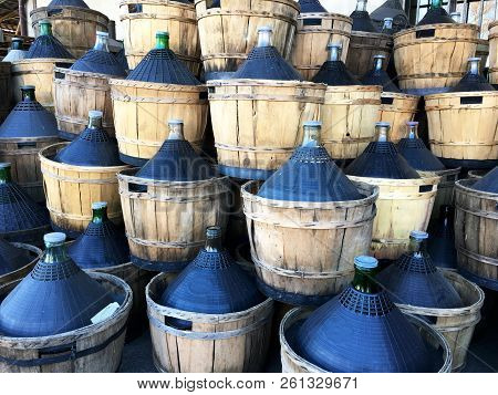 Wine Carboys Bottles Enclosed In Wickerwork Outside At Farm