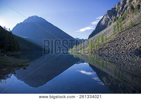 Reflection Of The Shore Of The Lake In The Watery Surface. Early Sunny Morning. The Large (lower) Sh