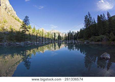 Reflection Of The Shore Of The Lake In The Watery Surface. Early Sunny Morning. The Large (lower) Sh