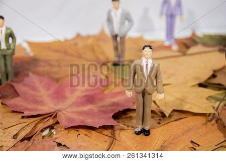 Small People Figures On Autumn Maple Leaves. Abstract Photo Of Autumn