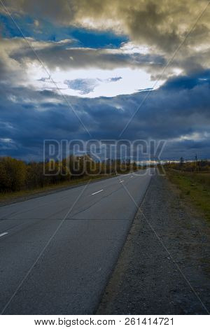 Deciduous Autumn Forest Grows Along An Asphalt Road With A Discontinuous Divided Strip Against The S