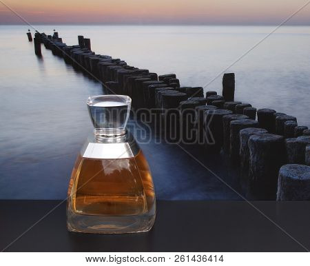 Fragrance For Ladies, Large Perfume Bottle In Front Of The Picture Of A Groyne In The Sea