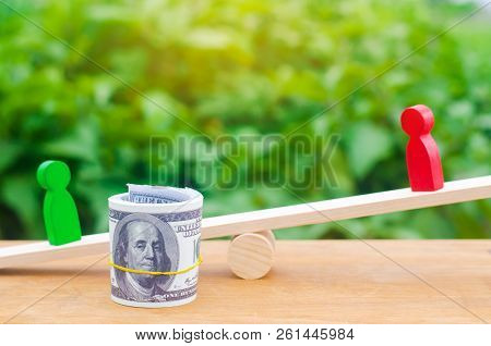 Wooden Figures Of People On Scales And Dollars Between Them. A Dispute Between Two Businessmen. Tria