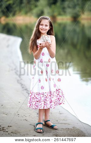 girl playing with a toy sailing ship by the river