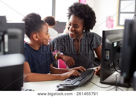 Teacher Helping Female High School Student Working at Screen In Computer Class