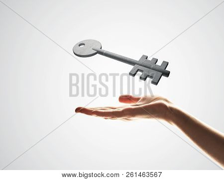 Close Up Of Hand Presenting Stone Key Symbol In Palm. Mixed Media
