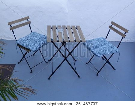 Two Spindly Chairs With Cushions And Small Square Table In Andalusian Courtyard Patio