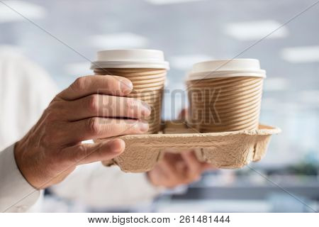 Businessman carrying coffee take out disposable cups for office meeting