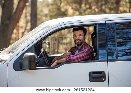 Bearded Driver Showing Thumb Up While Sitting In Pickup Truck In Forest