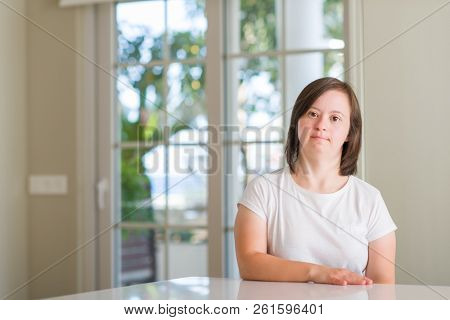 Down syndrome woman at home with serious expression on face. Simple and natural looking at the camera.