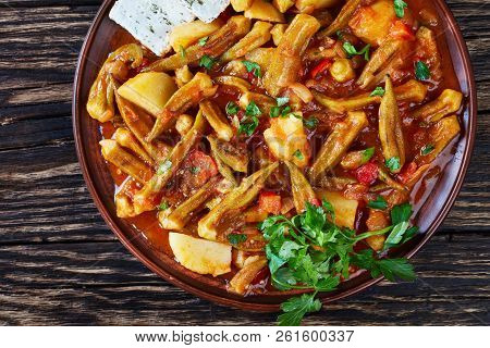 Okra Stewed With Tomatoes And Potatoes, Served With Feta Cheese Slices On A Earthenware Plate On A D