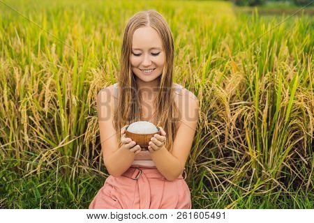 A Woman Is Holding A Cup Of Boiled Rice In A Wooden Cup On The Background Of A Ripe Rice Field